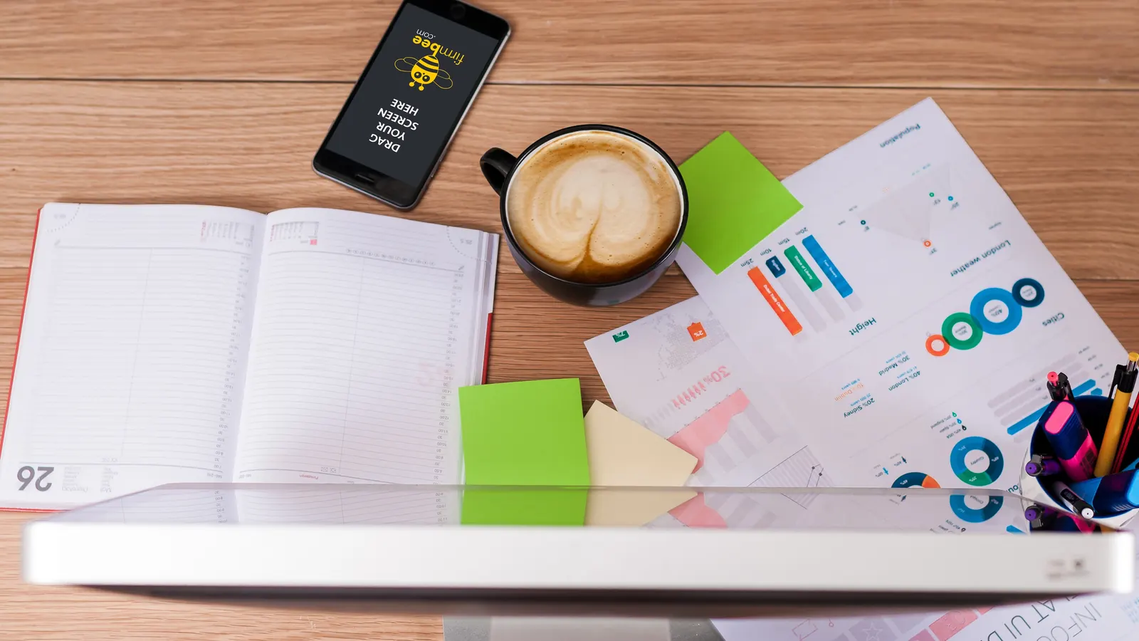 Desk with a notebook, coffee and printed marketing charts