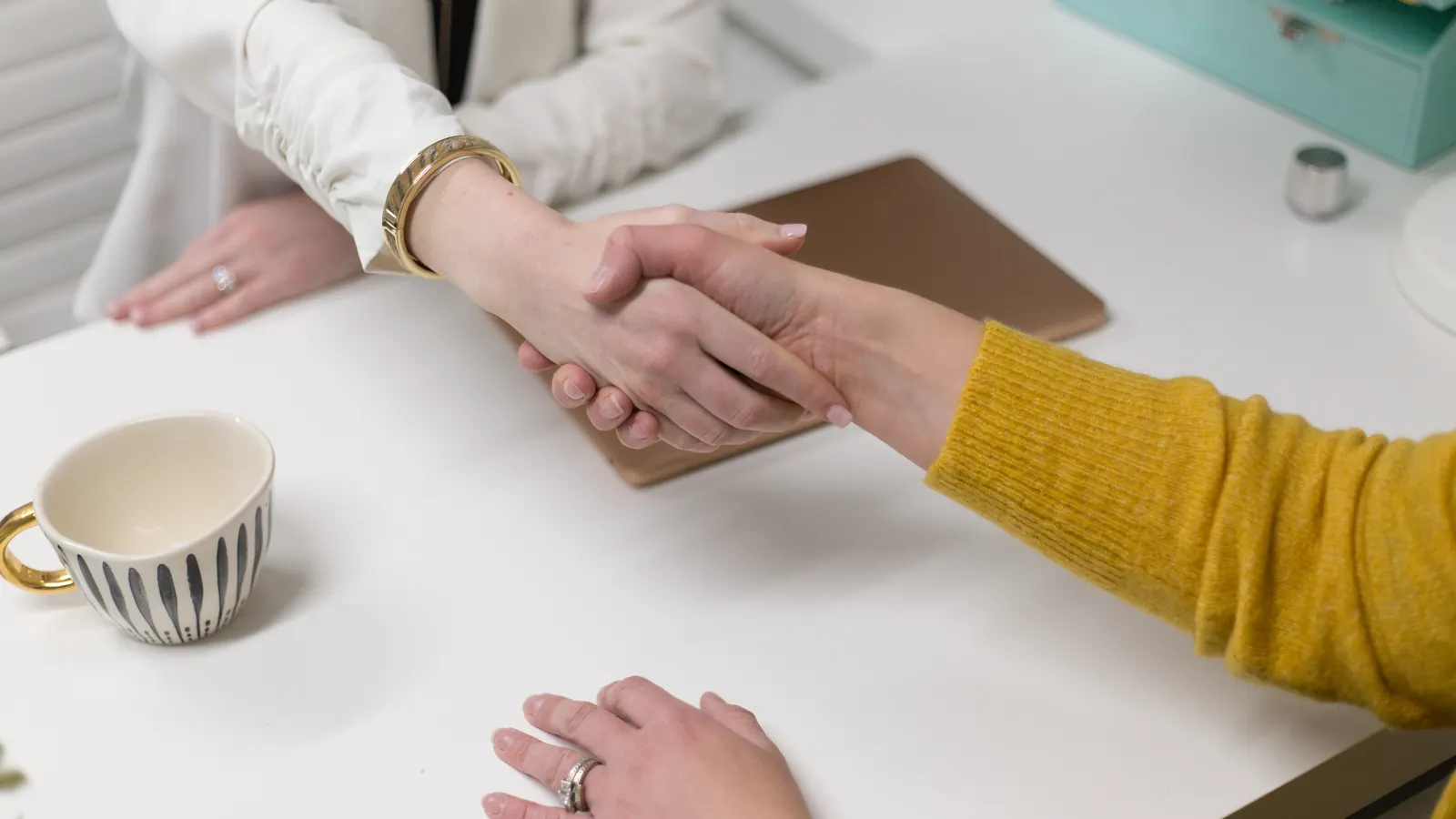 Two people shaking hands across a desk
