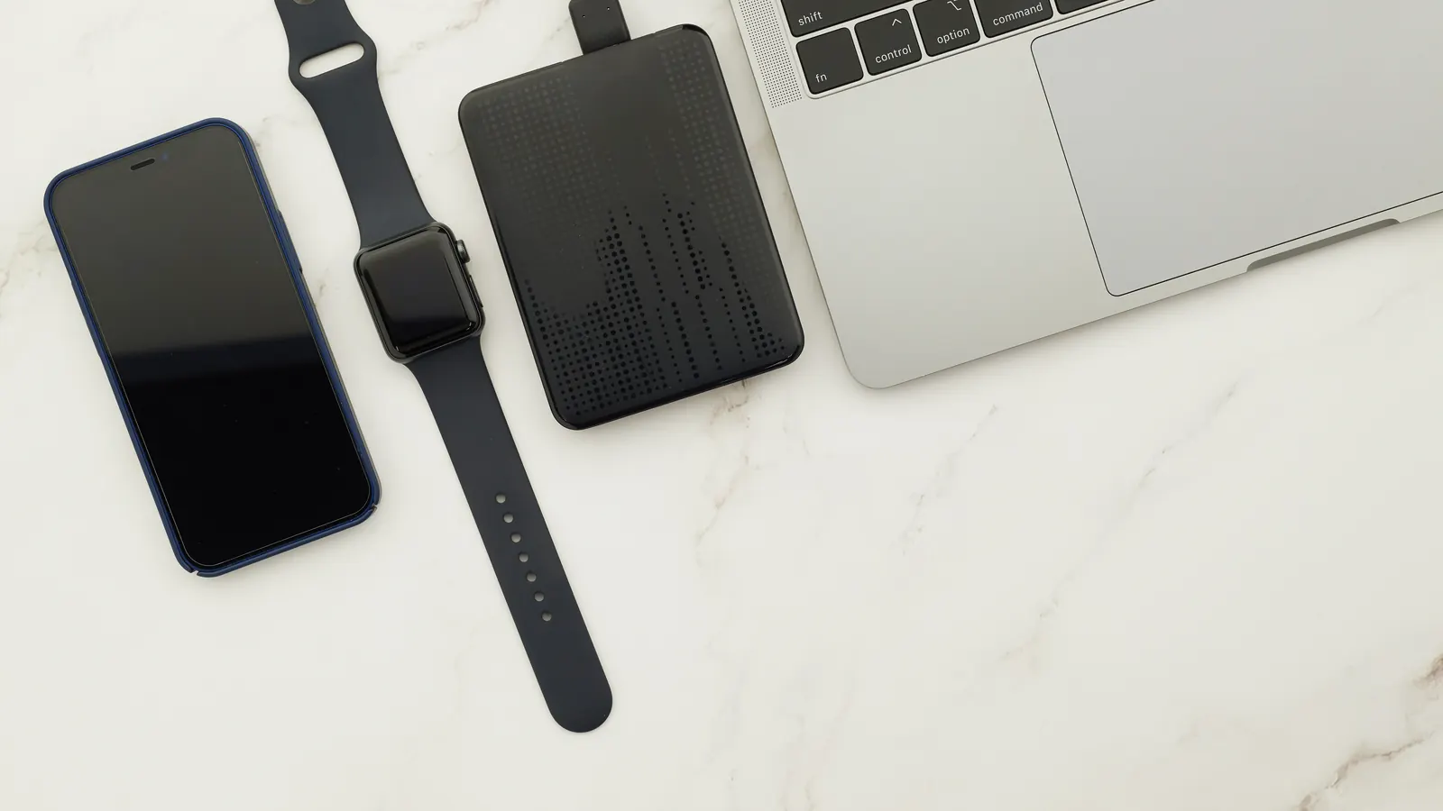 Smartphone, smartwatch, external drive and laptop on a marble desk