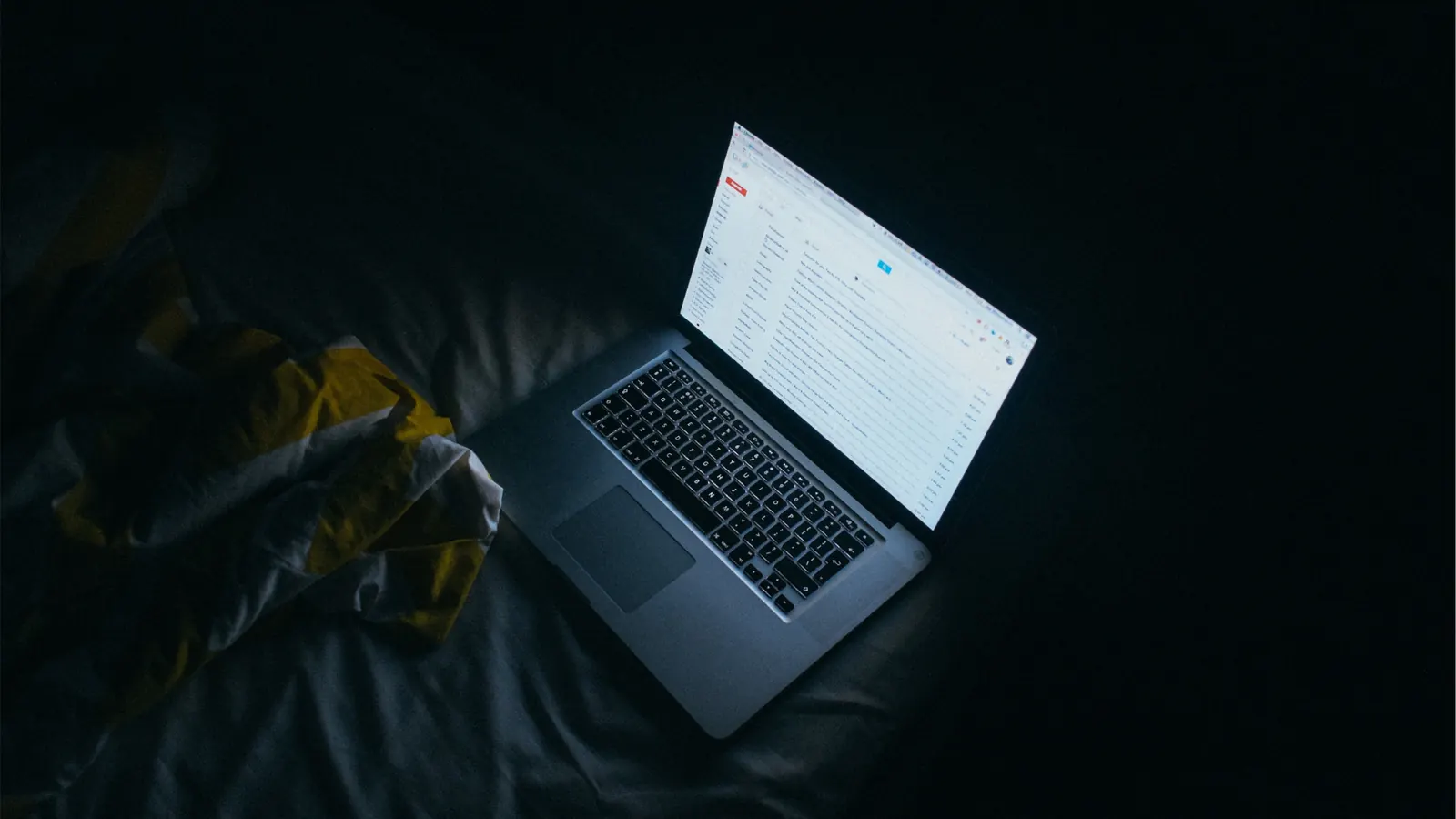 Laptop showing an email inbox in a dark room