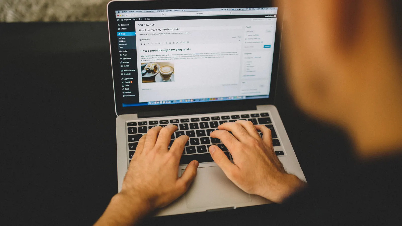 Hands typing on a laptop showing a website editor