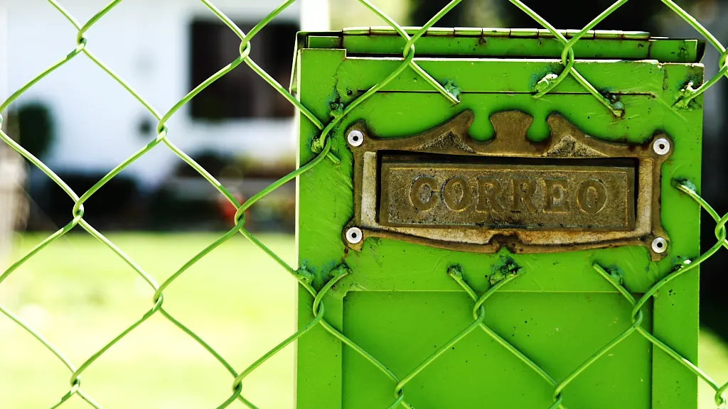 Green mailbox on a chain-link fence