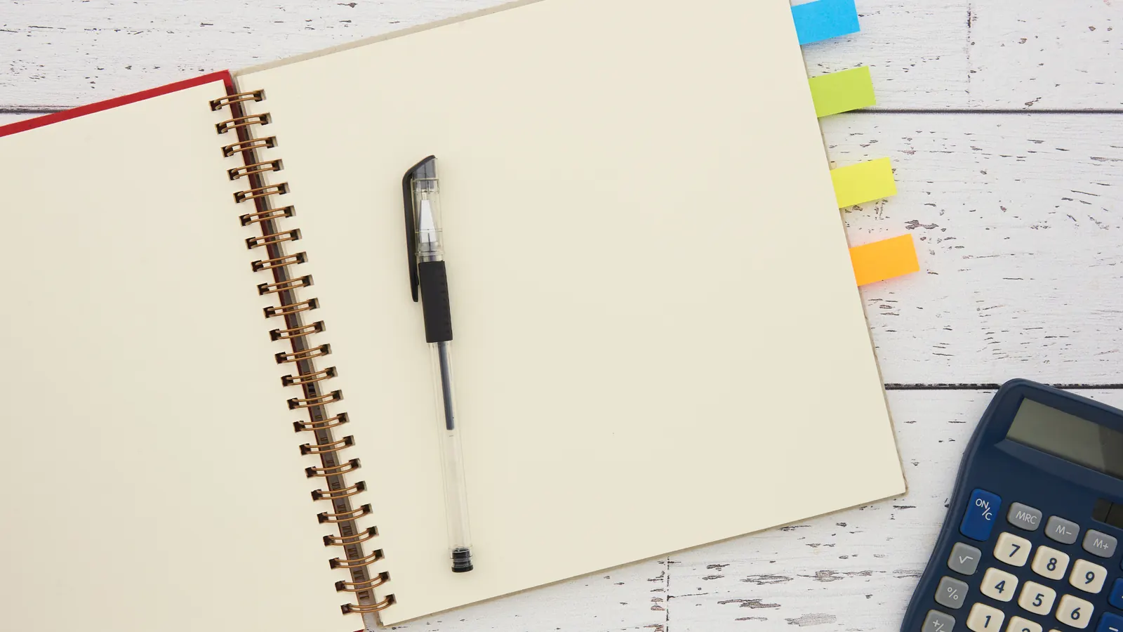 Notebook, pen and calculator on a white desk