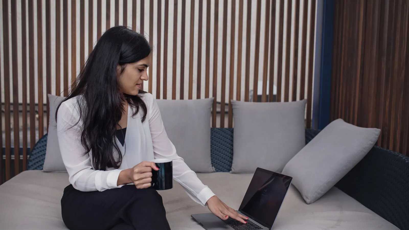 Woman with a coffee cup working on a laptop