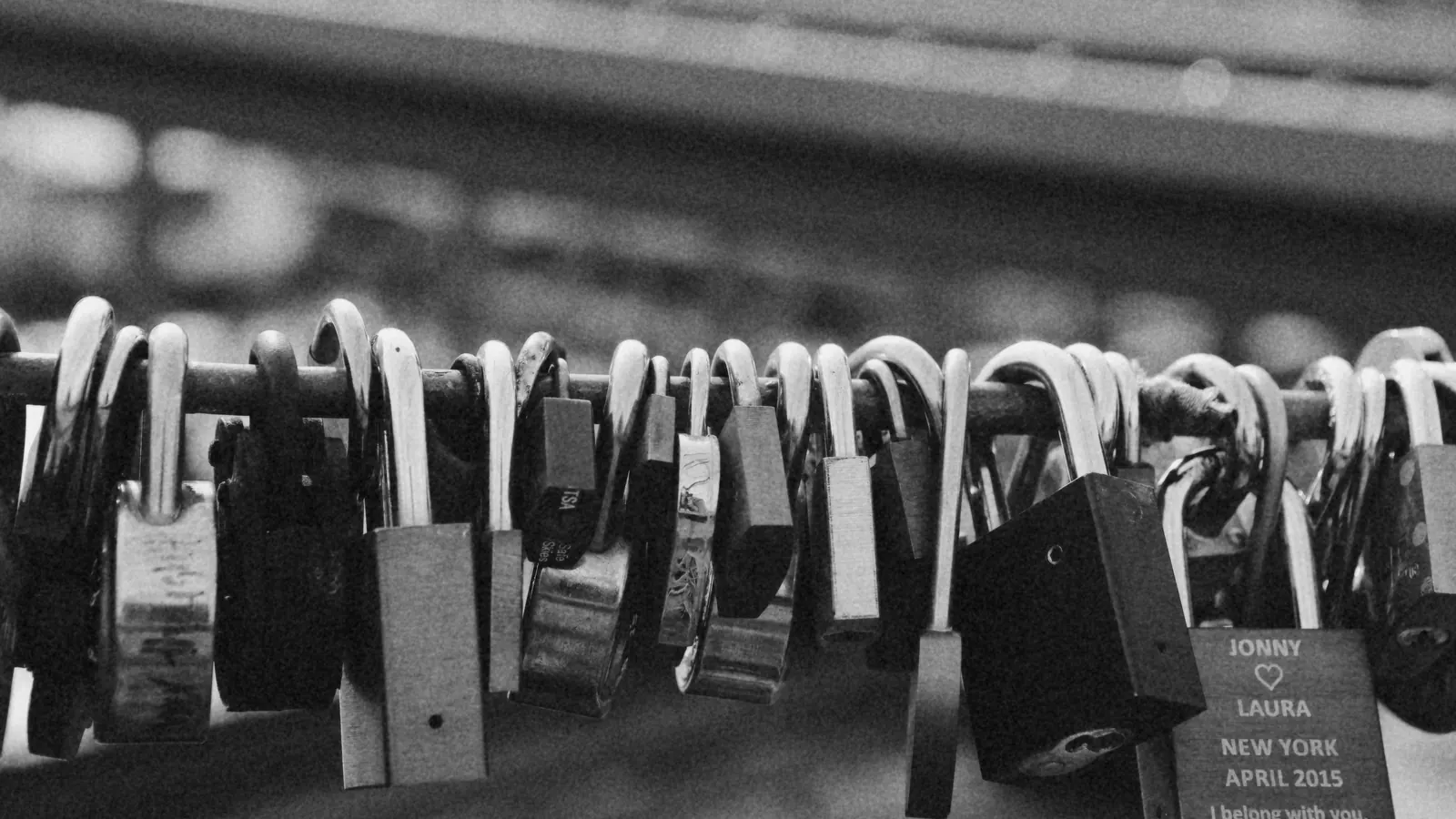 Many padlocks locked onto a railing