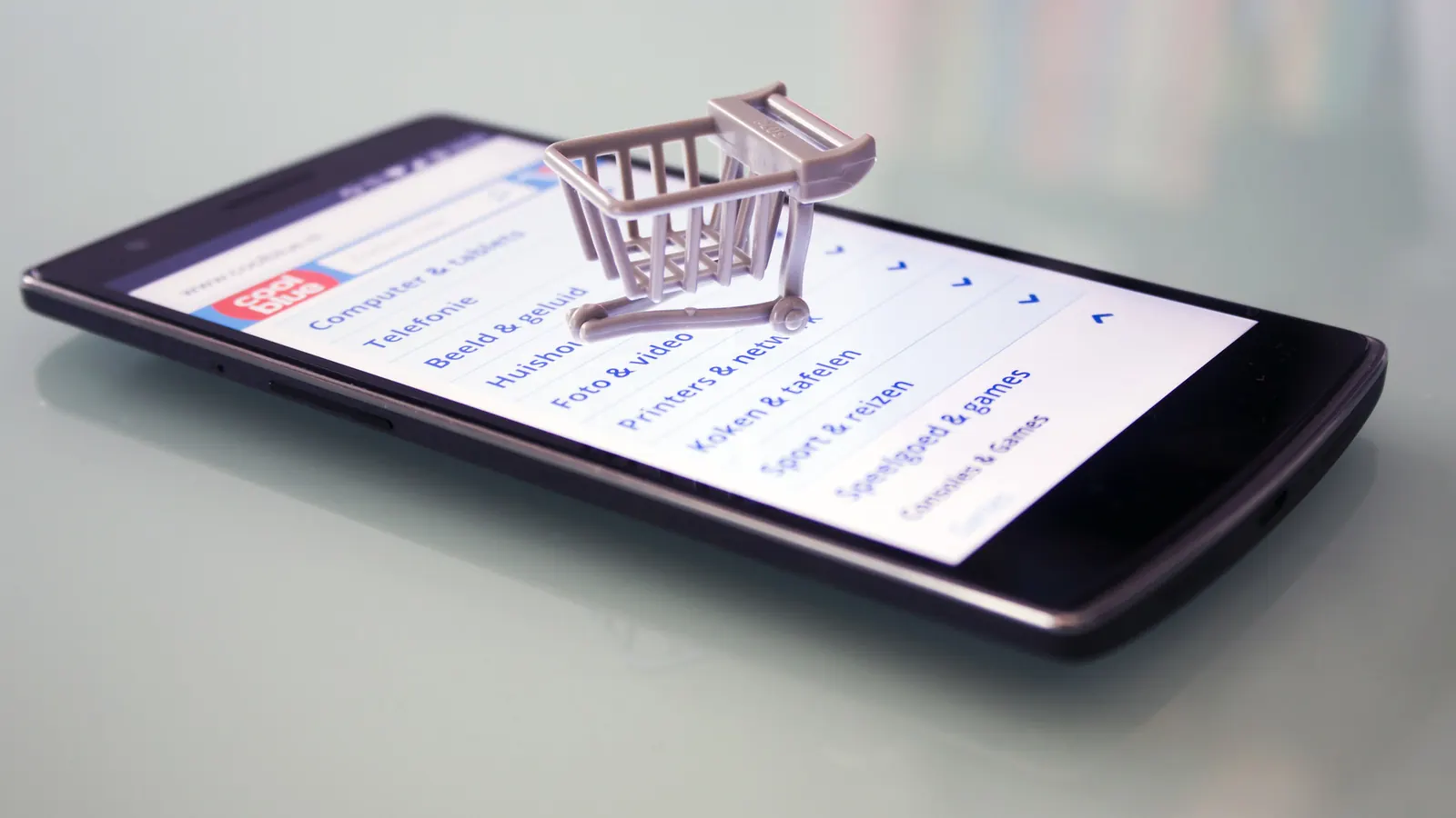 Smartphone showing an online shop with a small shopping cart on top