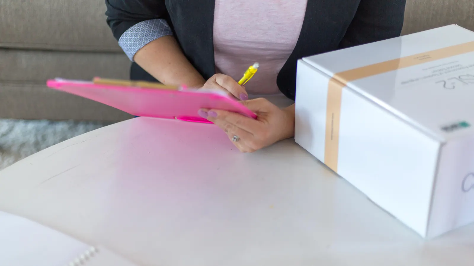 Person writing on a clipboard next to a parcel