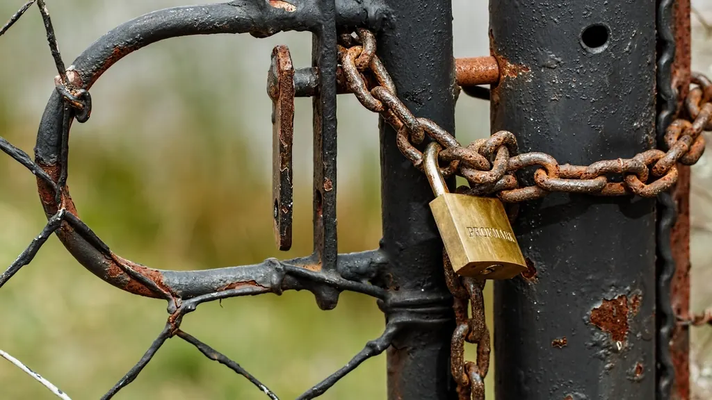 Padlock and chain securing a rusty gate